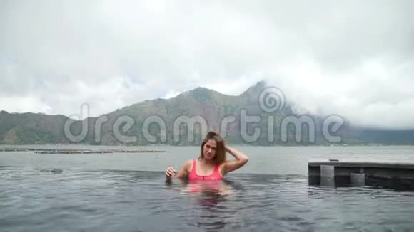 美丽的年轻女孩游泳池和湖和山景视频的预览图