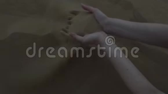 美丽的女人手摸着沙子沙子在风中飘扬视频的预览图