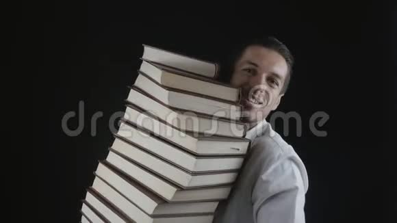 穿着白色衬衫的人手里拿着一叠书在黑暗的房间里手里拿着书的年轻商人视频的预览图