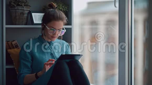 时髦的学生女孩坐在窗台上拿着一个小玩意视频的预览图