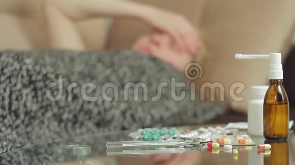 一位有疾病症状的成年妇女躺在毯子盖下的沙发上视频的预览图