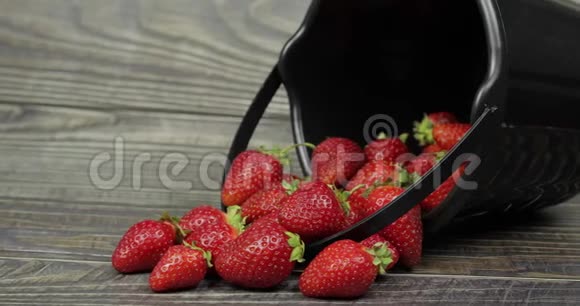 木桌上一个黑色小桶里的草莓合上视频的预览图