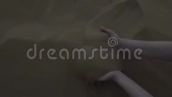 美丽的女人手摸着沙子沙子在风中飘扬视频的预览图