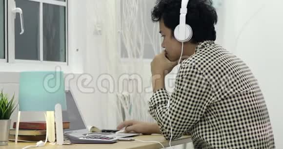 亚洲男人在家里用笔记本电脑努力工作视频的预览图