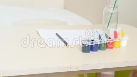 桌子上有水彩的银行勾面漆一张纸刷子准备画图儿童视频的预览图