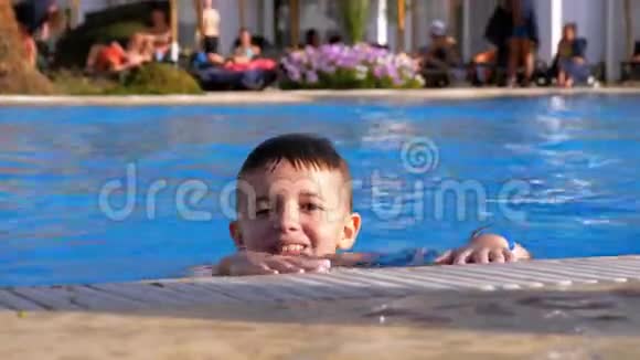 快乐的男孩在游泳池里和蓝色的水玩视频的预览图