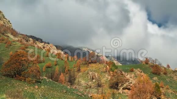 山脊上有厚厚的云层覆盖着新鲜的绿色草地和树木随着时间的推移有橙色的叶子视频的预览图