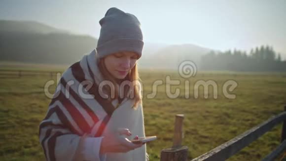 在日落时分年轻的女士在大自然中使用智能手机户外活动视频的预览图