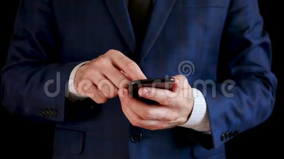 男性手举着一部黑色智能手机手指触摸手机的触摸屏商人通过视频的预览图