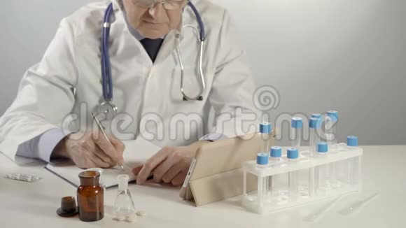 男医生用银笔和平板电脑在工作台上开处方视频的预览图