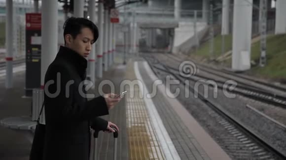 有电话的韩国男子站在室外火车站视频的预览图