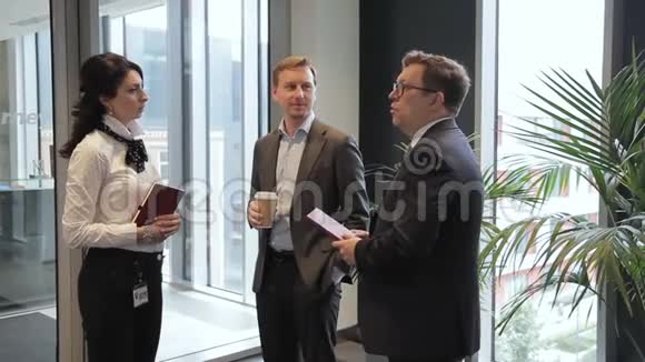 三名员工正站在大公司的大厅里交谈视频的预览图