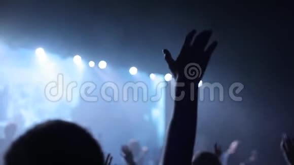一群年轻人在音乐会上举手的特写镜头他们在模糊的舞台前唱歌视频的预览图