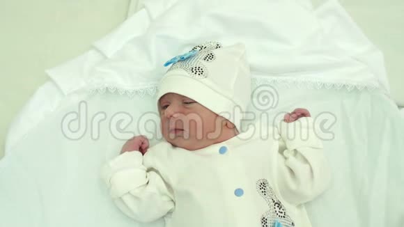 戴着白色帽子的新生婴儿躺在床上视频的预览图