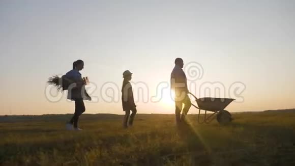 年轻的家庭在他们的农场户外玩得很开心日落时分推着蔬菜手推车的园丁家庭视频的预览图
