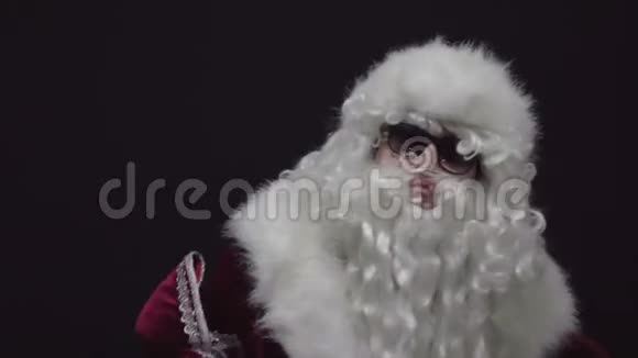 一个自信的圣诞老人的肖像用红色圣诞老人套装折叠手臂黑色背景视频的预览图