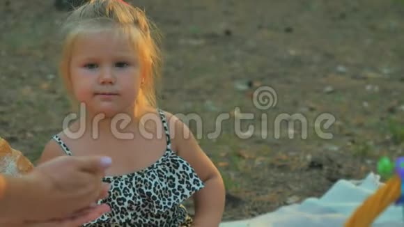 小女孩吃羊角面包试着从女手里拿出一颗五颜六色的糖果视频的预览图
