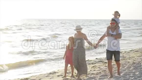 两个女儿和快乐的母亲和父亲一起在海滩上散步在暑假牵手视频的预览图