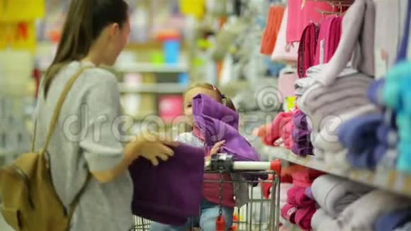 超级市场年轻幸福家庭特写肖像可爱的小女孩坐在超市的购物车里年轻的女人视频的预览图