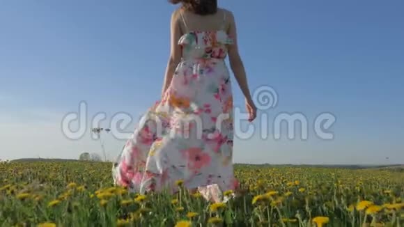 女人穿着随风飘舞的衣服在一片盛开的黄色田野上漫步视频的预览图