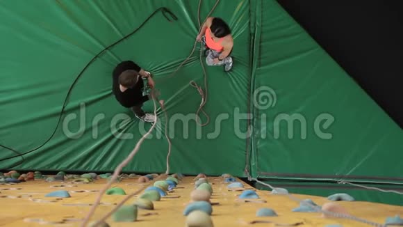 男人和女人在室内练习攀岩前把绳子绑在身体上视频的预览图