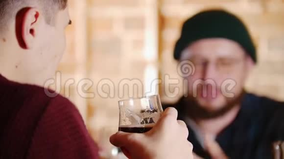 戴眼镜的胡子男在酒吧和他的朋友聊天啤酒视频的预览图