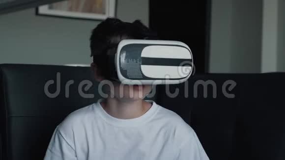 一个快乐的男孩戴着虚拟现实眼镜在家里玩游戏看电影虚拟现实眼镜新技术视频的预览图