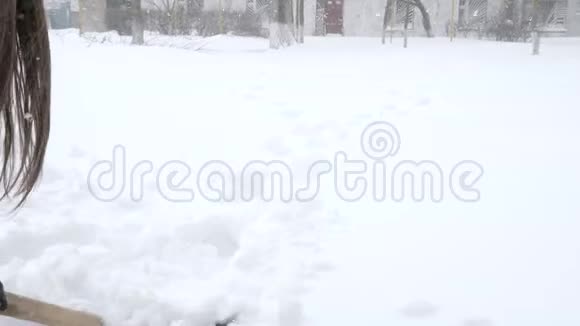 下雪的天气手里拿着铁锹的女人正在冬天的暴风雪中清理雪堆上的道路视频的预览图