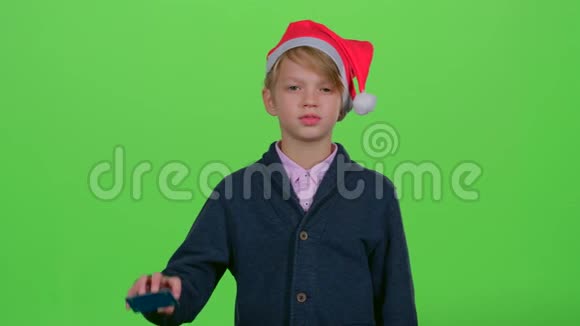 戴着信用卡的少年戴着新年帽子表示不喜欢然后喜欢在绿色屏幕上视频的预览图