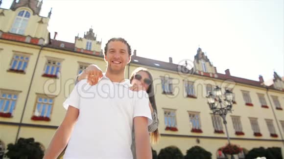 强壮的男人背着他的女友和微笑有趣的夫妇在外面享受温暖的阳光日视频的预览图