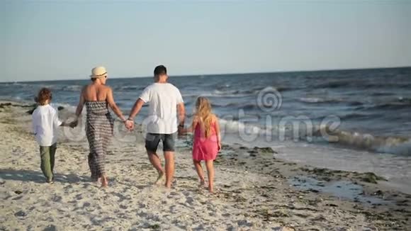 在海滨度假期间四位快乐家庭成员在海滩散步的后景视频的预览图