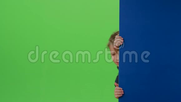 男孩从旁边的木板上出现挥舞着手在绿色的屏幕上呼唤他视频的预览图