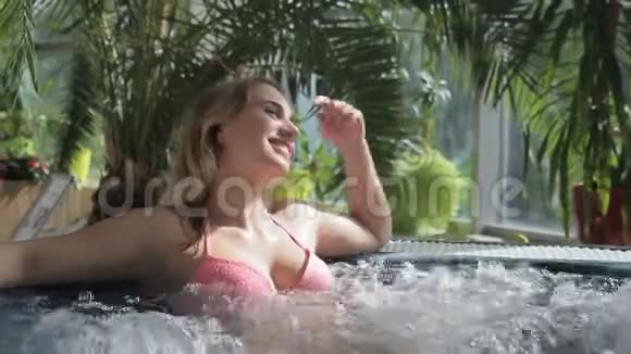 年轻女子躺在温泉区的泡泡池里视频的预览图