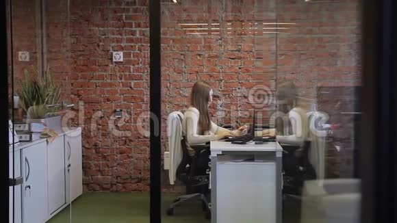 女秘书在舒适的接待办公室工作有砖墙和玻璃门视频的预览图