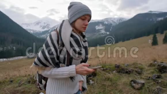 年轻漂亮的女士在山谷散步时使用智能手机应用程序视频的预览图