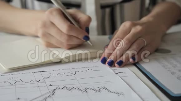 女专家写在笔记本上看图表而坐在办公室视频的预览图