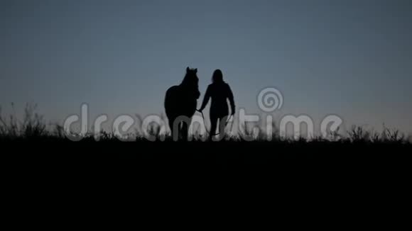 傍晚时分一名妇女带着一匹马朝摄像机走去视频的预览图