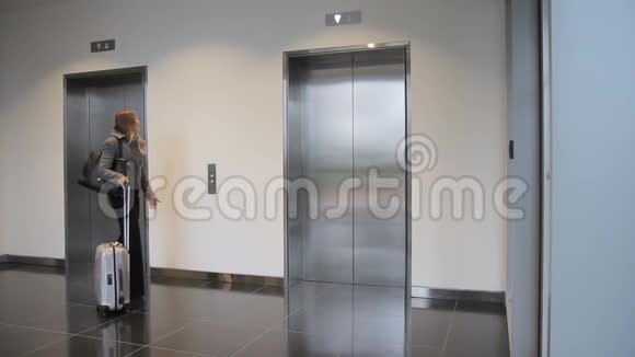 带手提箱的年轻女子走进电梯室内视频的预览图