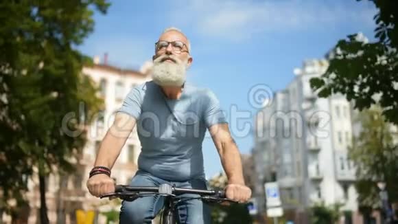 有思想的长胡子的人骑着自行车在街上视频的预览图