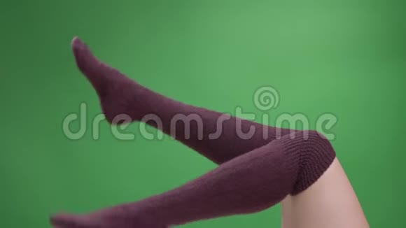 穿着可爱的红袜子的少女美腿特写镜头嬉戏地移动着背部被隔离在绿色上视频的预览图