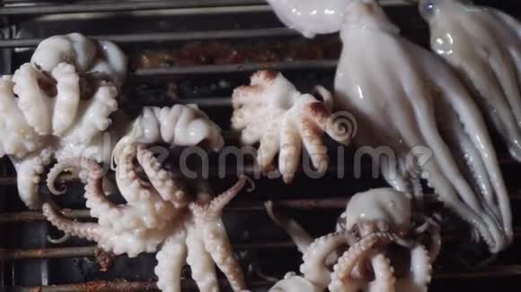 在亚洲夜市烤架上煮章鱼当地供应商准备海鲜烧烤出售街头食品视频的预览图
