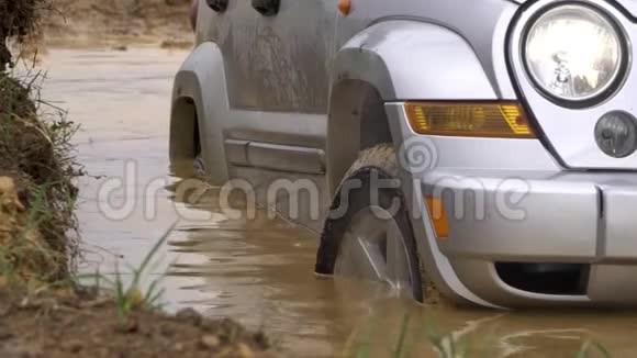美丽的汽车在乡村上空滑行强大的SUV留下了一个水的深洞从侧面转动前轮视频的预览图