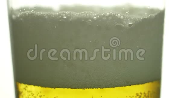 啤酒被倒入一个玻璃杯中在墙上泡沫流淌在白色的背景上慢镜头拍摄啤酒节视频的预览图