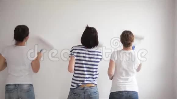 美丽的姐妹在休闲服装在家修理三女画墙的后景视频的预览图