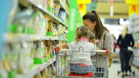 年轻漂亮妈妈和小孩在超市买食物的肖像幸福家庭的侧观视频的预览图