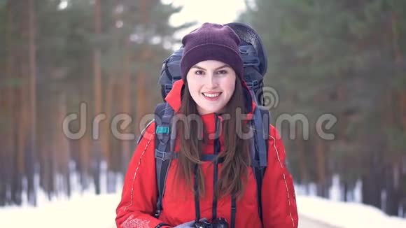 那个旅游女孩正在转过身在冬天的森林里沿着公路开始她的路视频的预览图