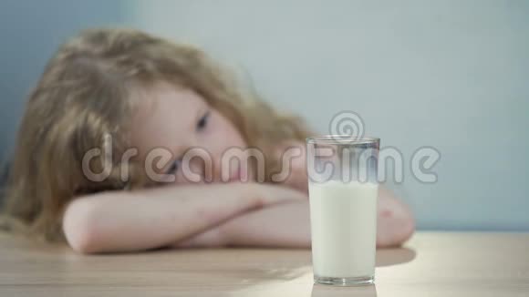 悲伤的女孩子坐在桌子旁看着一杯牛奶早餐视频的预览图