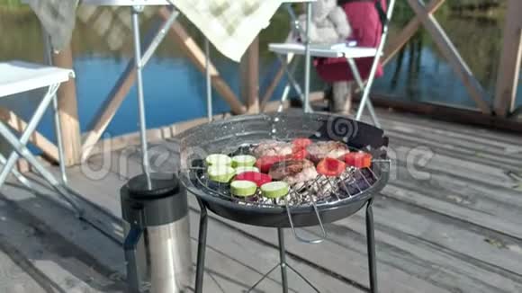 烤蔬菜和肉在独木桥上河边野餐周末寒冷的天气野营旅游视频的预览图