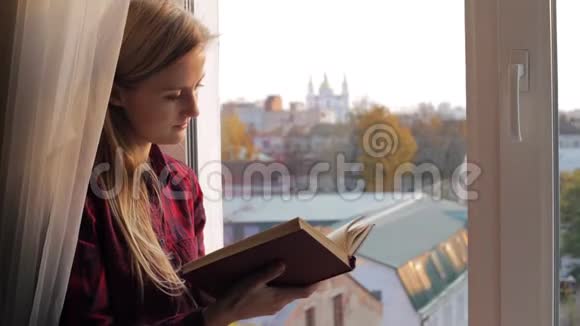 日落时分幸福的女人在窗边看书视频的预览图