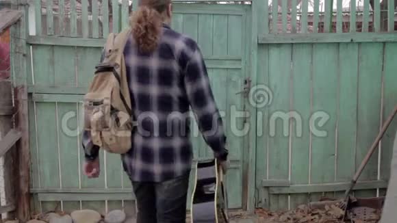 一个男人带着吉他独自离开家毛茸茸的人从老房子的大门出来视频的预览图